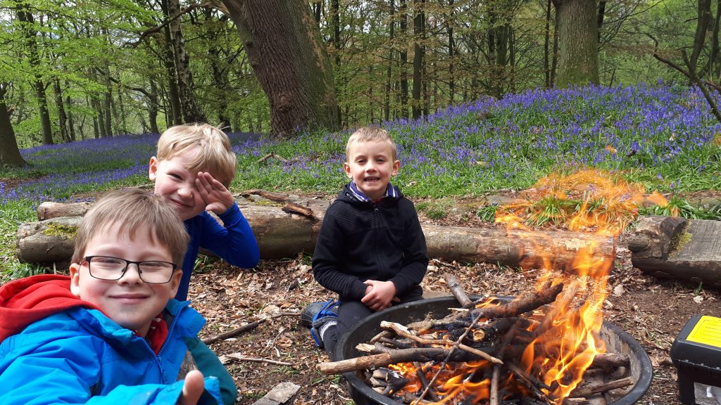 Three young boys around a campfire